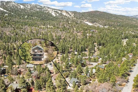 an aerial view of a house with a yard and mountain view in back