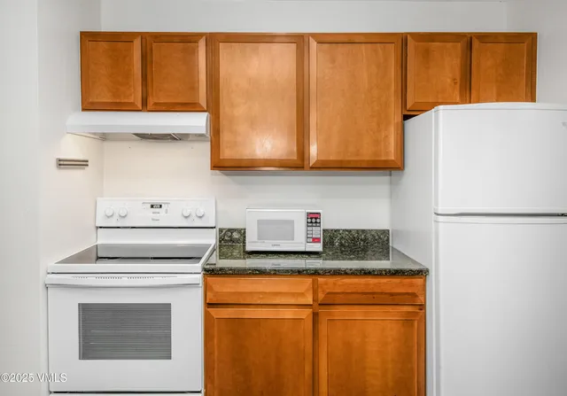 a kitchen with granite countertop cabinets and refrigerator