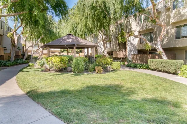 a backyard of a house with table and chairs under an umbrella