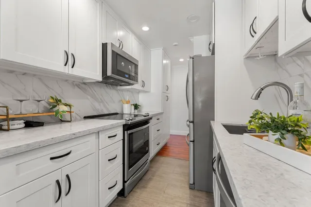 a kitchen with stainless steel appliances kitchen island granite countertop a refrigerator and a stove top oven