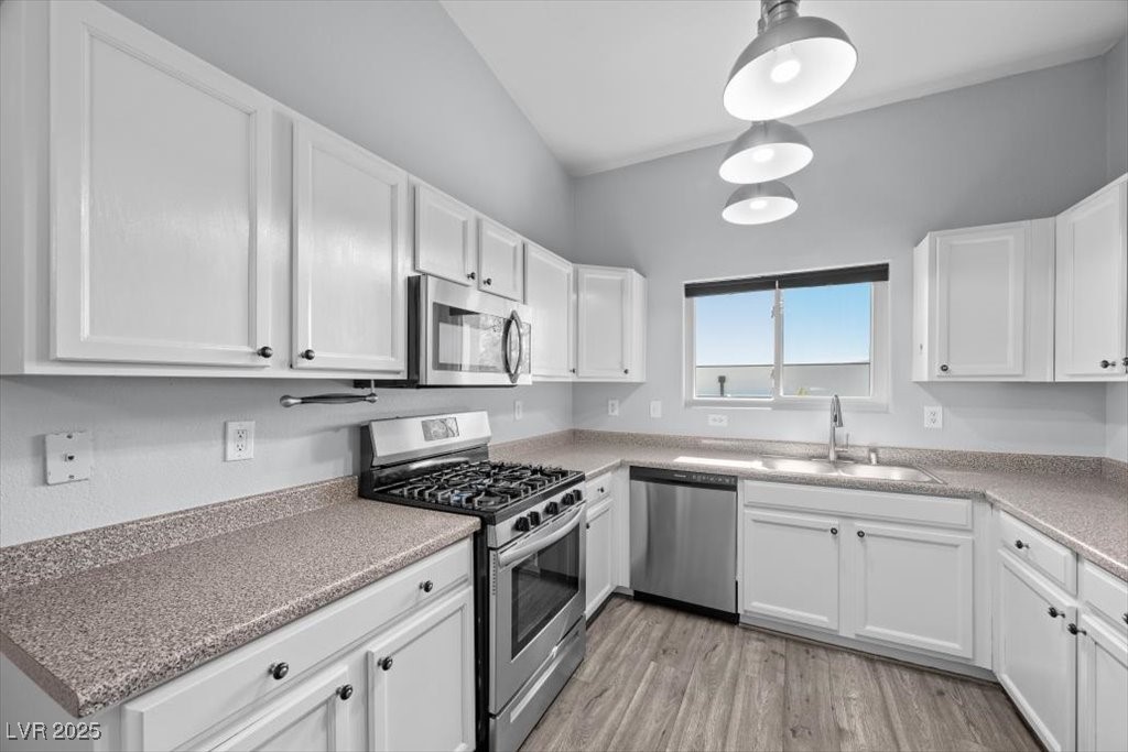 2152 Quarry Ridge Street, Unit 207 Las Vegas, NV 89117 - Photo 11 of 37 Kitchen with appliances with stainless steel finishes, white cabinetry, light wood-style flooring, and light countertops