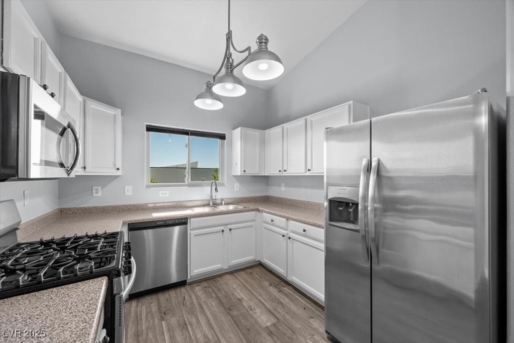 2152 Quarry Ridge Street, Unit 207 Las Vegas, NV 89117 - Photo 12 of 37 Kitchen featuring appliances with stainless steel finishes, light wood finished floors, hanging light fixtures, and white cabinetry