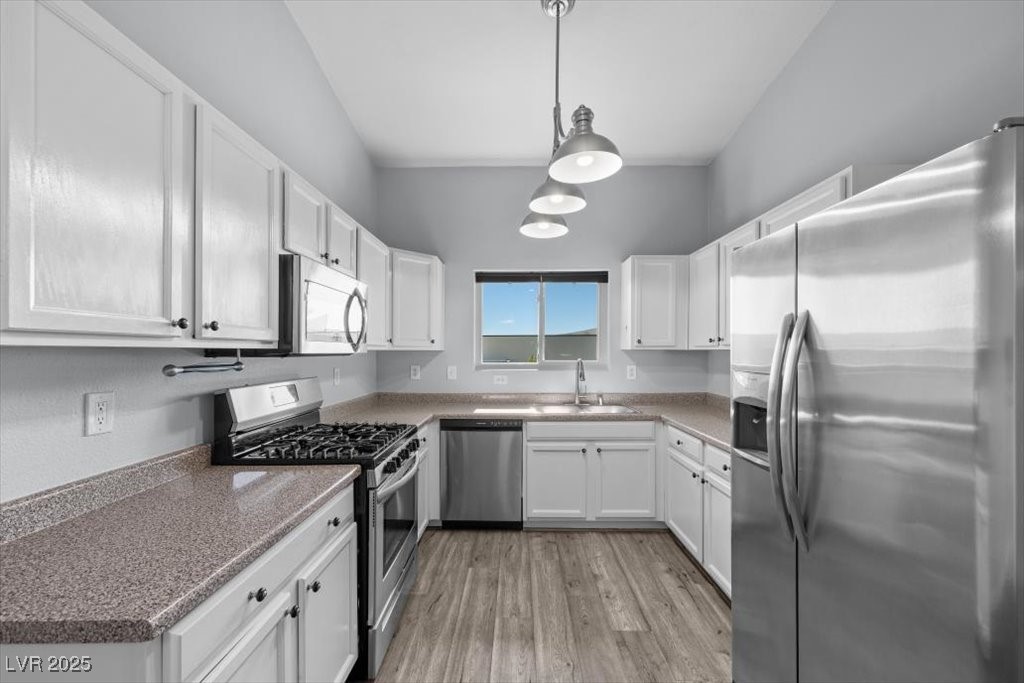 2152 Quarry Ridge Street, Unit 207 Las Vegas, NV 89117 - Photo 13 of 37 Kitchen with stainless steel appliances, light wood-style floors, white cabinets, and hanging light fixtures