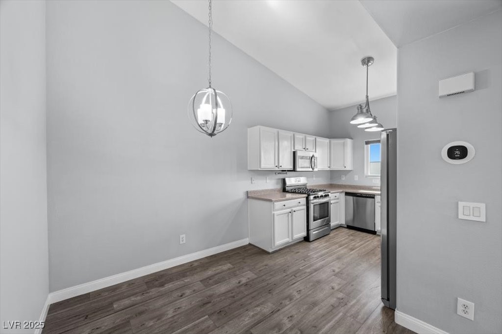 2152 Quarry Ridge Street, Unit 207 Las Vegas, NV 89117 - Photo 15 of 37 Dining Area/ Kitchen with appliances with stainless steel finishes, light countertops, white cabinetry, dark wood finished floors, and hanging light fixtures