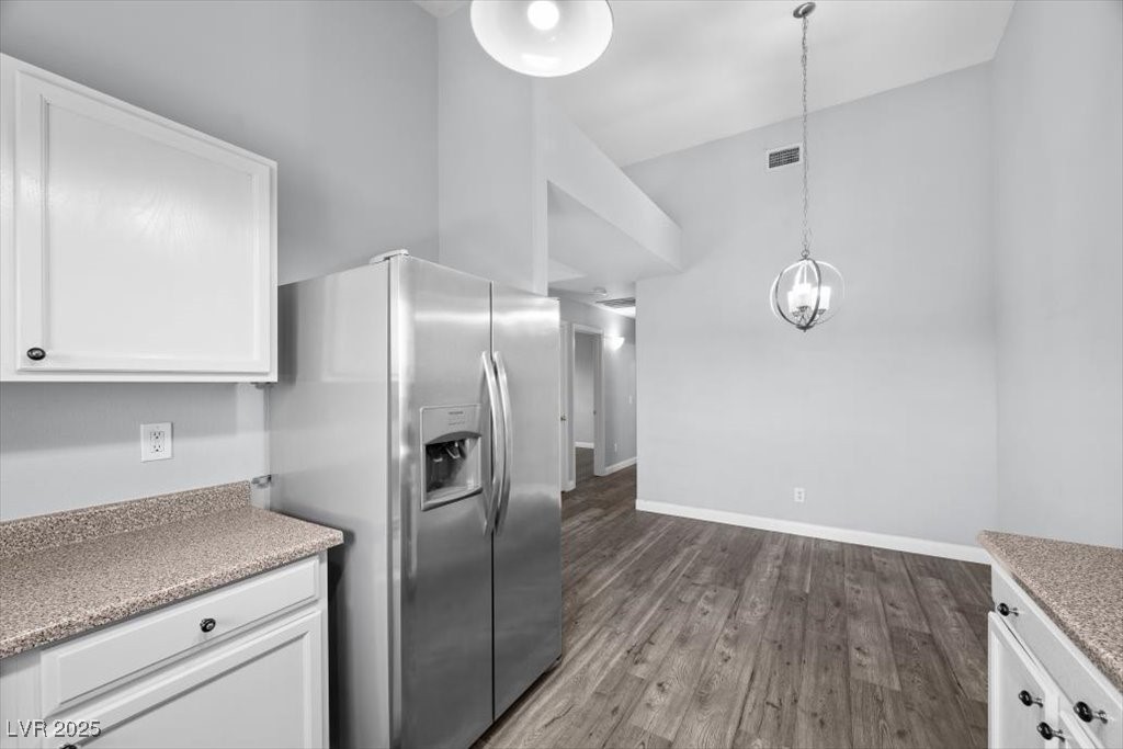 2152 Quarry Ridge Street, Unit 207 Las Vegas, NV 89117 - Photo 16 of 37 Kitchen with stainless steel fridge, white cabinetry, dark wood finished floors, and hanging light fixtures