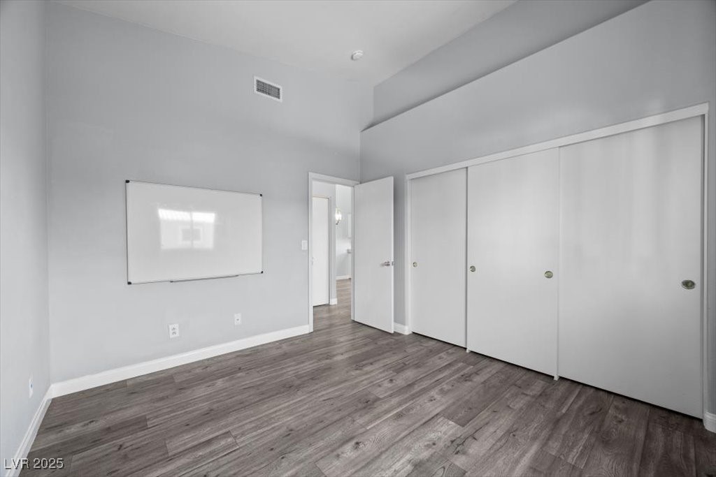 2152 Quarry Ridge Street, Unit 207 Las Vegas, NV 89117 - Photo 26 of 37 Unfurnished bedroom featuring wood finished floors, a towering ceiling, and a closet