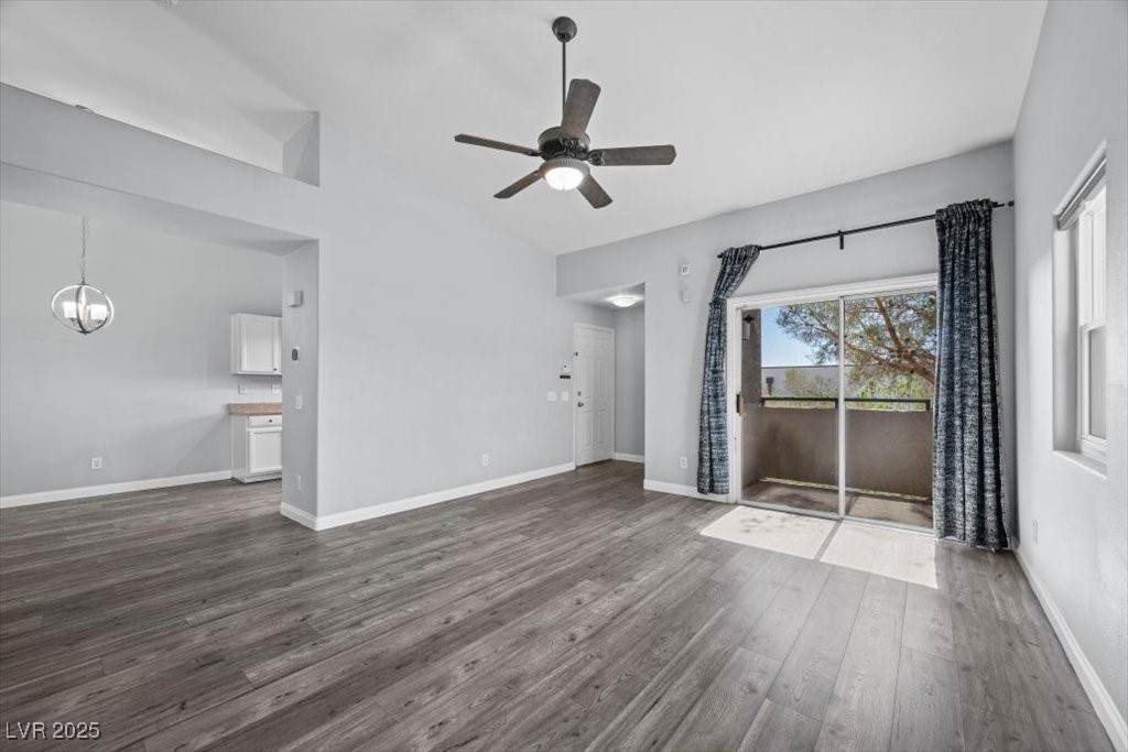 2152 Quarry Ridge Street, Unit 207 Las Vegas, NV 89117 - Photo 8 of 37 Unfurnished living room with dark wood-style flooring, ceiling fan, and a chandelier
