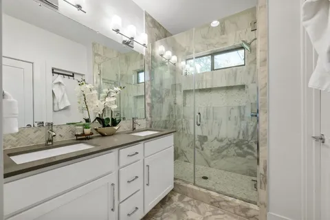 a bathroom with a double vanity sink mirror and shower