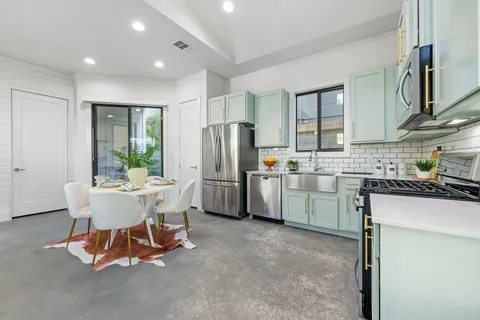 a kitchen with a refrigerator a stove a sink and a dining table with chairs