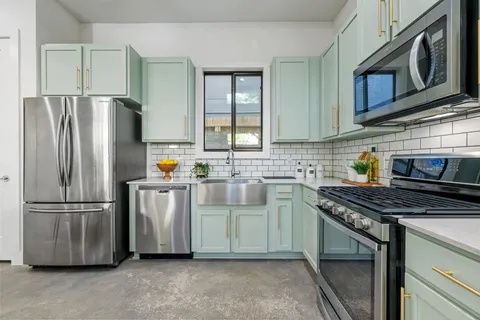 a kitchen with stainless steel appliances granite countertop a refrigerator a stove a sink and a microwave