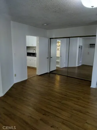 a view of empty room with wooden floor and kitchen