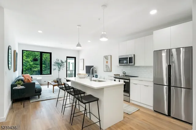 a kitchen with stainless steel appliances granite countertop a refrigerator a stove a sink dishwasher a dining table and chairs with wooden floor