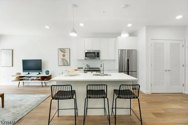 a kitchen with stainless steel appliances a stove a refrigerator a microwave a dining table and chairs