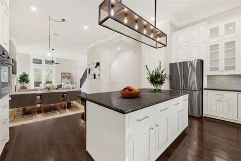 a kitchen with stainless steel appliances kitchen island granite countertop a sink a refrigerator and a wooden floor