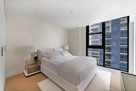 a spacious bedroom with a bed a dresser and a large mirror