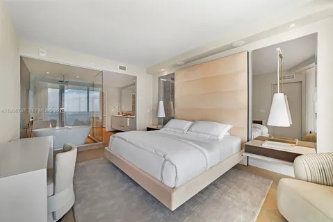 a bedroom with a bed lamp and a large window