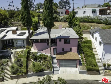 a front view of a house with a yard and potted plants