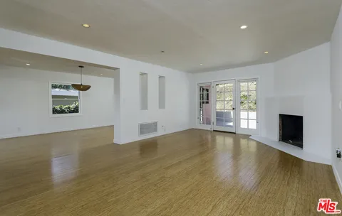 a view of empty room with wooden floor and window
