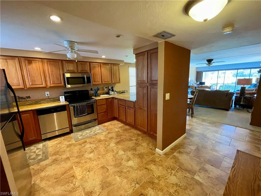 a kitchen with stainless steel appliances kitchen island granite countertop a refrigerator and stove