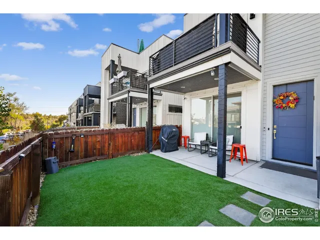 a view of a backyard with couches plants and wooden fence