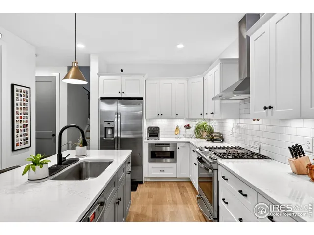 a kitchen with a sink a stove a refrigerator and white cabinets