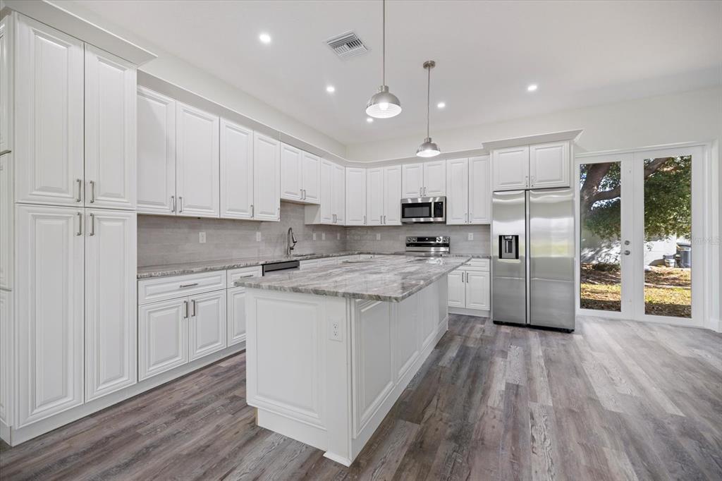 3525 McIntosh Road Sarasota, FL 34232 - Photo 12 of 40 a kitchen with stainless steel appliances granite countertop a refrigerator a sink dishwasher a stove and white cabinets with wooden floor