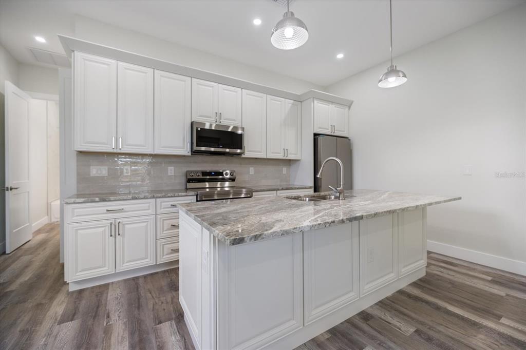 3525 McIntosh Road Sarasota, FL 34232 - Photo 18 of 40 a kitchen with kitchen island granite countertop a sink stainless steel appliances and white cabinets