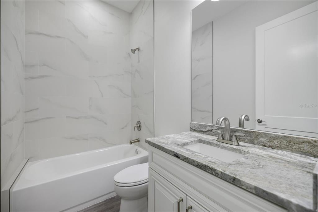 3525 McIntosh Road Sarasota, FL 34232 - Photo 27 of 40 a bathroom with a granite countertop sink a toilet and bathtub