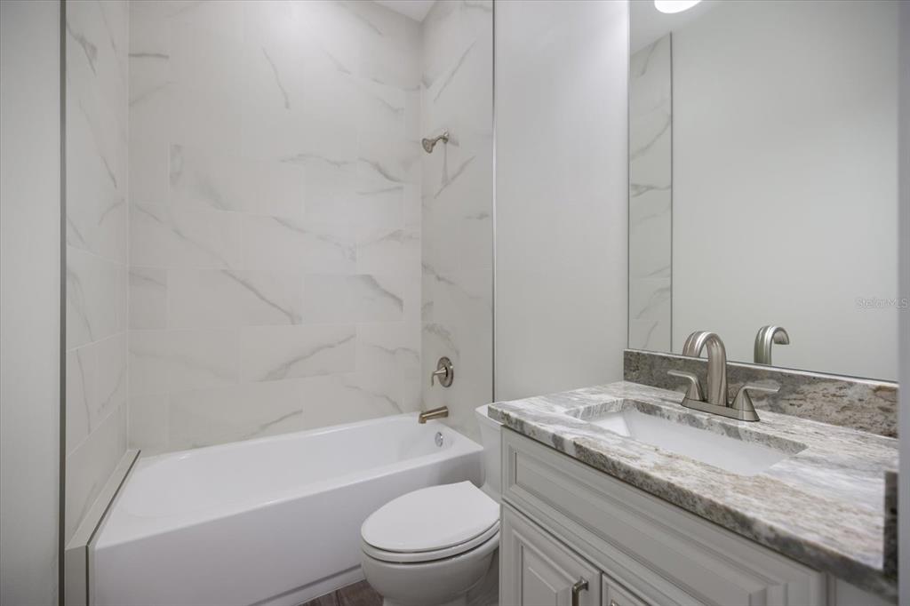 3525 McIntosh Road Sarasota, FL 34232 - Photo 28 of 40 a bathroom with a granite countertop toilet a sink and a bathtub