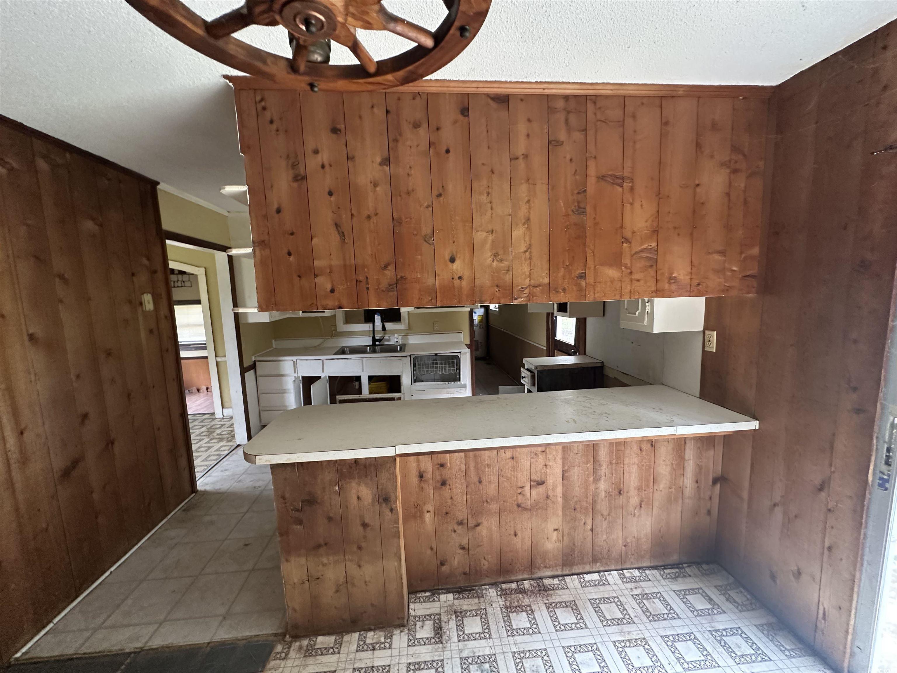 11185 Old Pee Dee Road Hemingway, SC 29554 - Photo 12 of 15 Kitchen with wooden walls, a textured ceiling, light countertops, a peninsula, and ornamental molding
