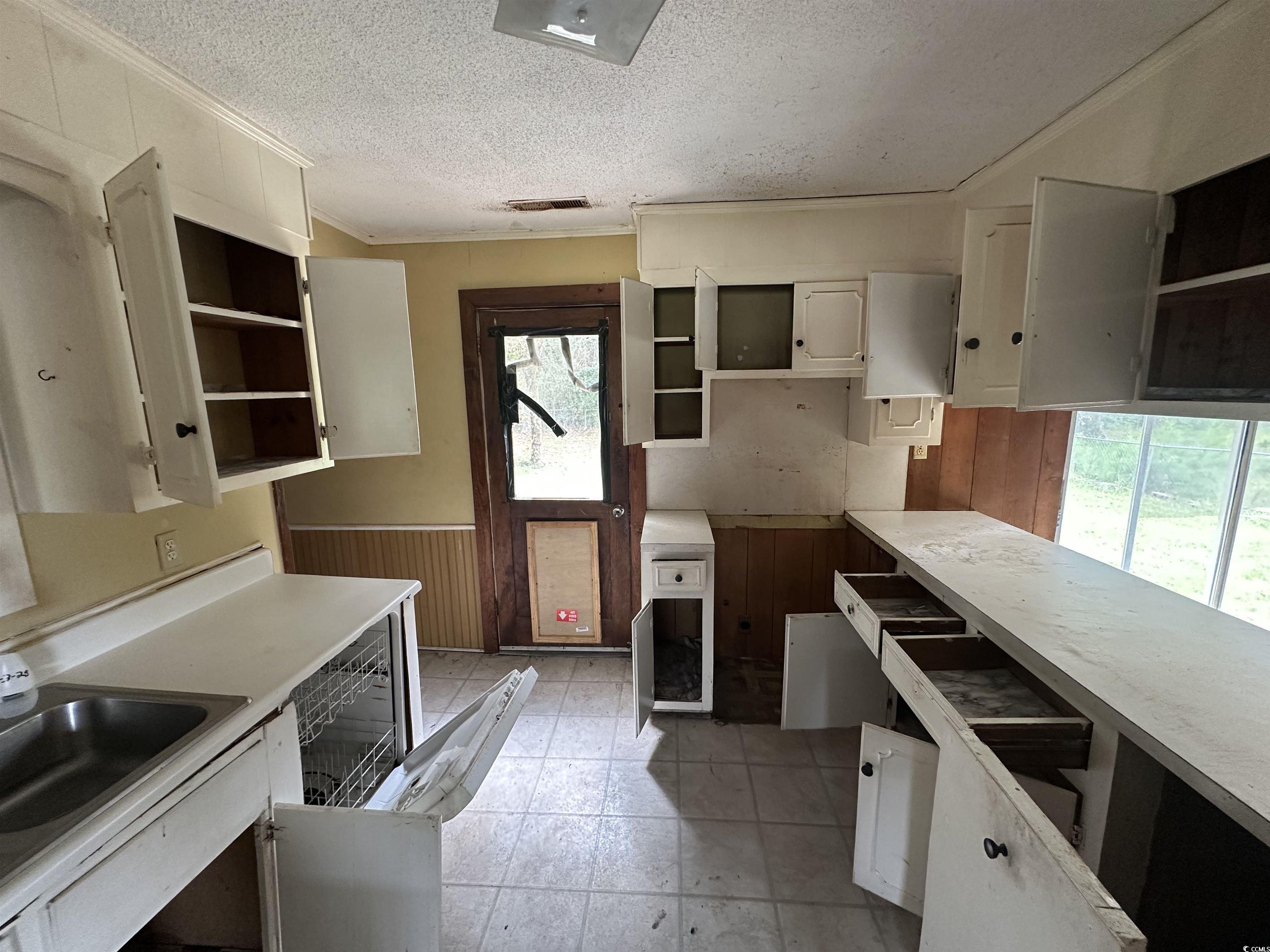 11185 Old Pee Dee Road Hemingway, SC 29554 - Photo 13 of 15 Kitchen featuring white cabinetry, a textured ceiling, light countertops, wainscoting, and open shelves
