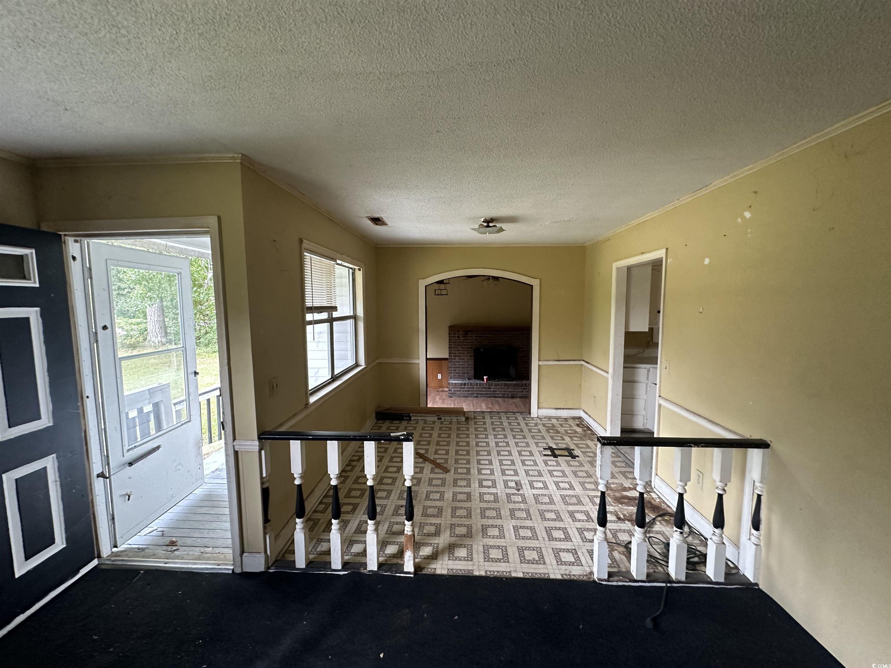 11185 Old Pee Dee Road Hemingway, SC 29554 - Photo 2 of 15 Foyer with light colored carpet, a fireplace, a textured ceiling, and crown molding