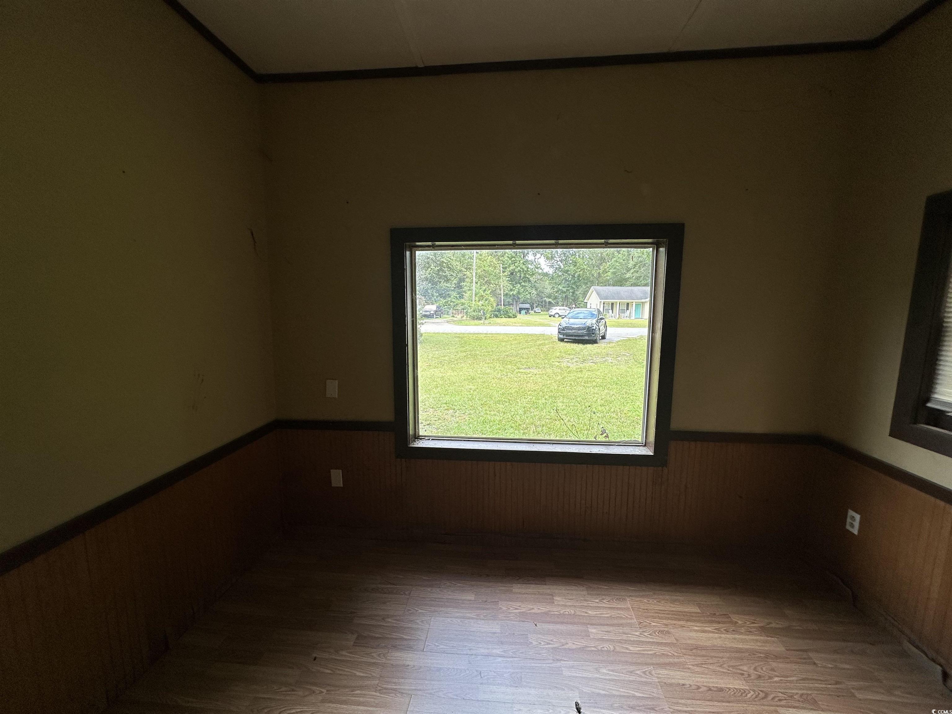 11185 Old Pee Dee Road Hemingway, SC 29554 - Photo 6 of 15 Unfurnished room featuring wainscoting, wood walls, and wood finished floors
