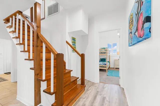a view of staircase with lots of frames on wall and wooden floor