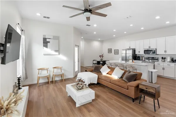 a living room with furniture kitchen view and a flat screen tv