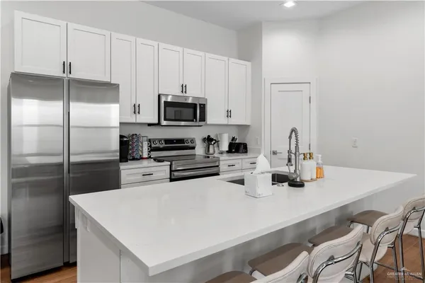 a kitchen with stainless steel appliances a sink a stove a refrigerator cabinets and a dining table