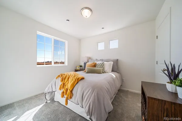 a bedroom with a bed and a potted plant on dresser