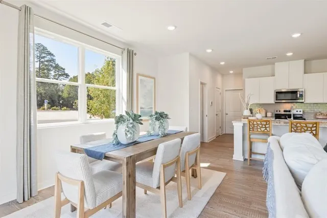 a dining room with furniture a large window and stainless steel appliances