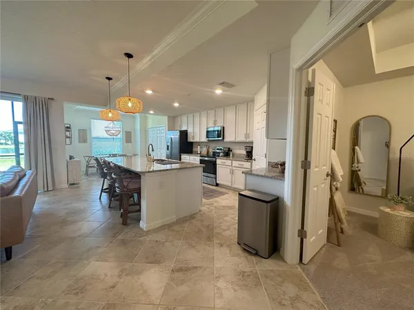 a kitchen with stainless steel appliances granite countertop a sink a stove a refrigerator a dining table and chairs