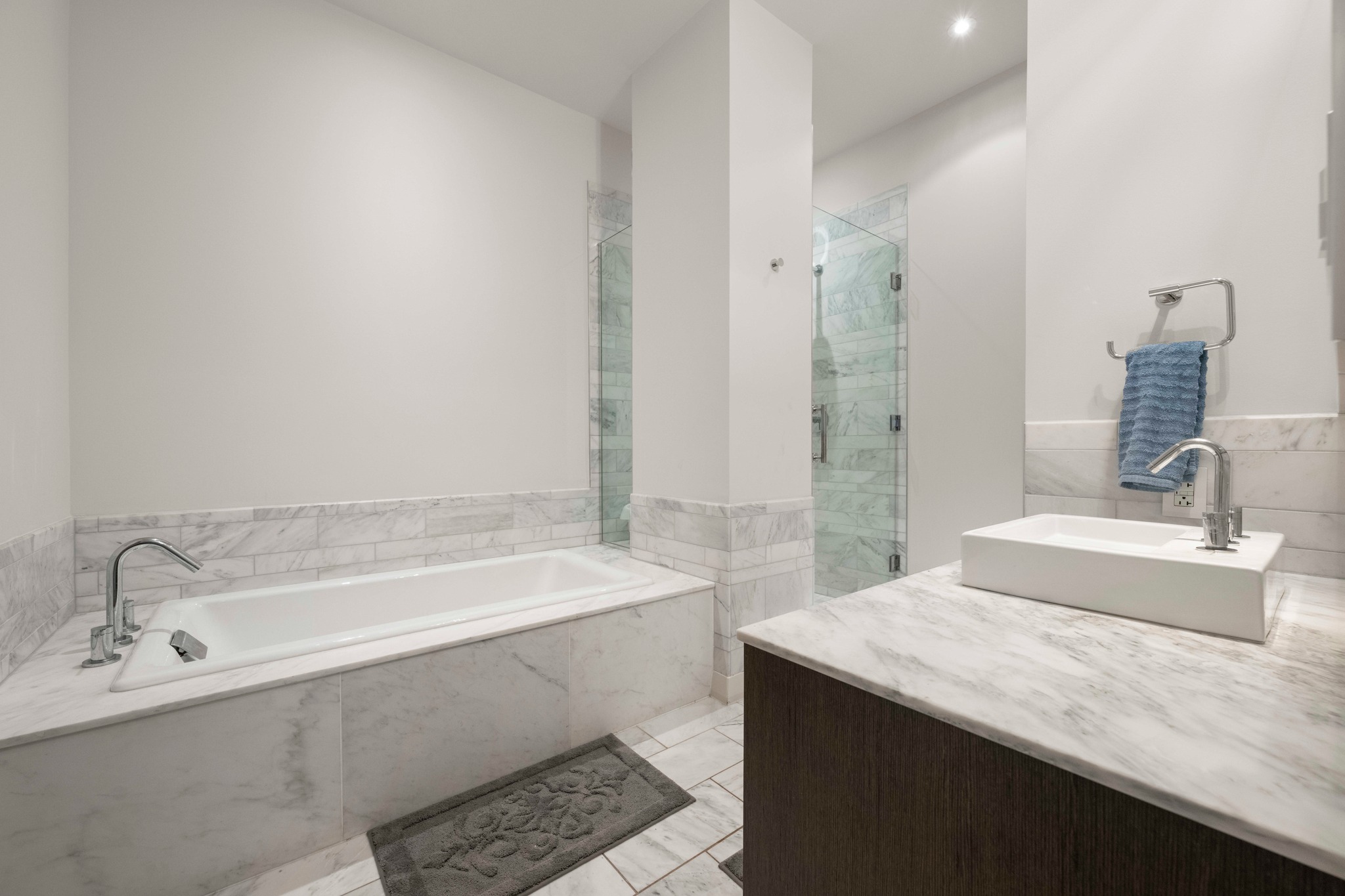 210 Lavaca Street, Unit 2706 Austin, TX 78701 - Photo 29 of 32 Contemporary bathroom featuring a built-in tub with chrome fixtures, a glass-enclosed shower, a rectangular vessel sink, and a dark wood-finish vanity