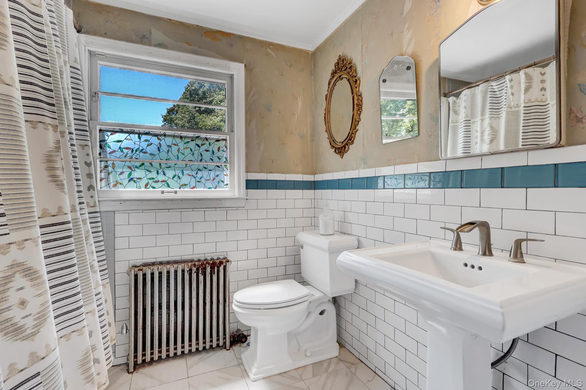 100 Elwood Road Northport, NY 11768 - Photo 21 of 39 Bathroom featuring white subway tile walls, a blue accent tile band, and a white pedestal sink with a brushed nickel faucet