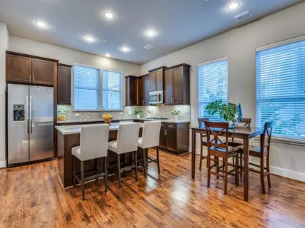 a kitchen with kitchen island a dining table chairs stainless steel appliances and cabinets