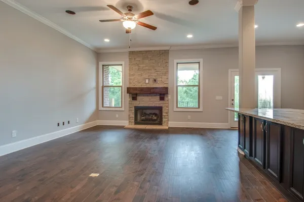 an empty room with wooden floor fireplace and windows