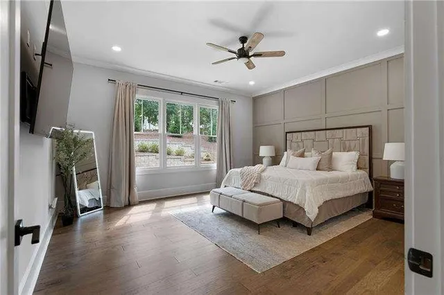 a spacious bedroom with a bed and a flat tv screen on dresser