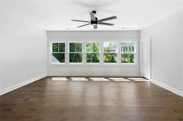 an empty room with wooden floor and windows