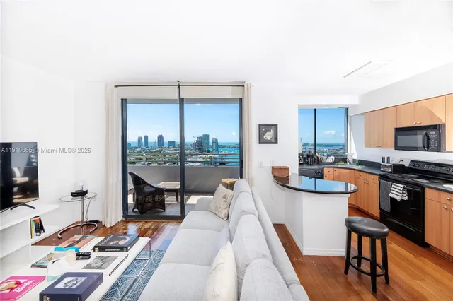 a living room with furniture a flat screen tv and a floor to ceiling window