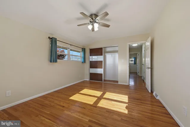 a view of empty room with wooden floor and ceiling fan