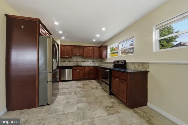 a kitchen with stainless steel appliances granite countertop a refrigerator and a stove top oven