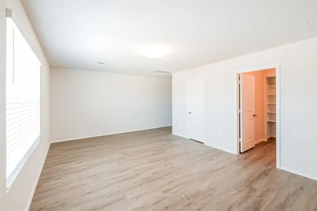 an empty room with wooden floor & windows