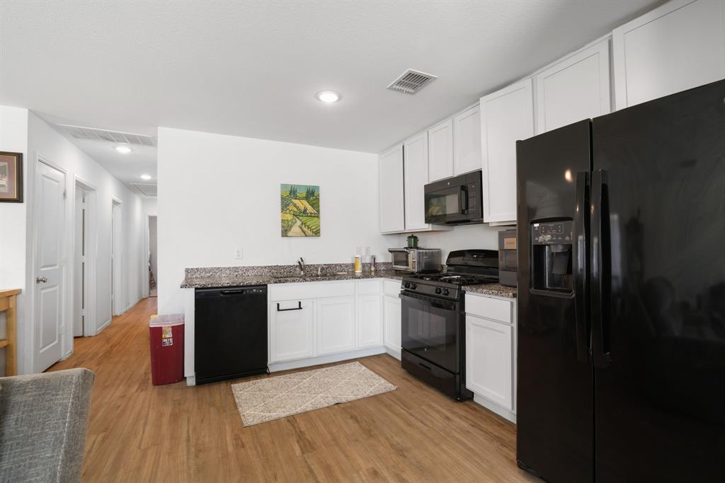 1445 Sterling Way Ferris, TX 75125 - Photo 4 of 17 a kitchen with granite countertop a refrigerator stove top oven and sink